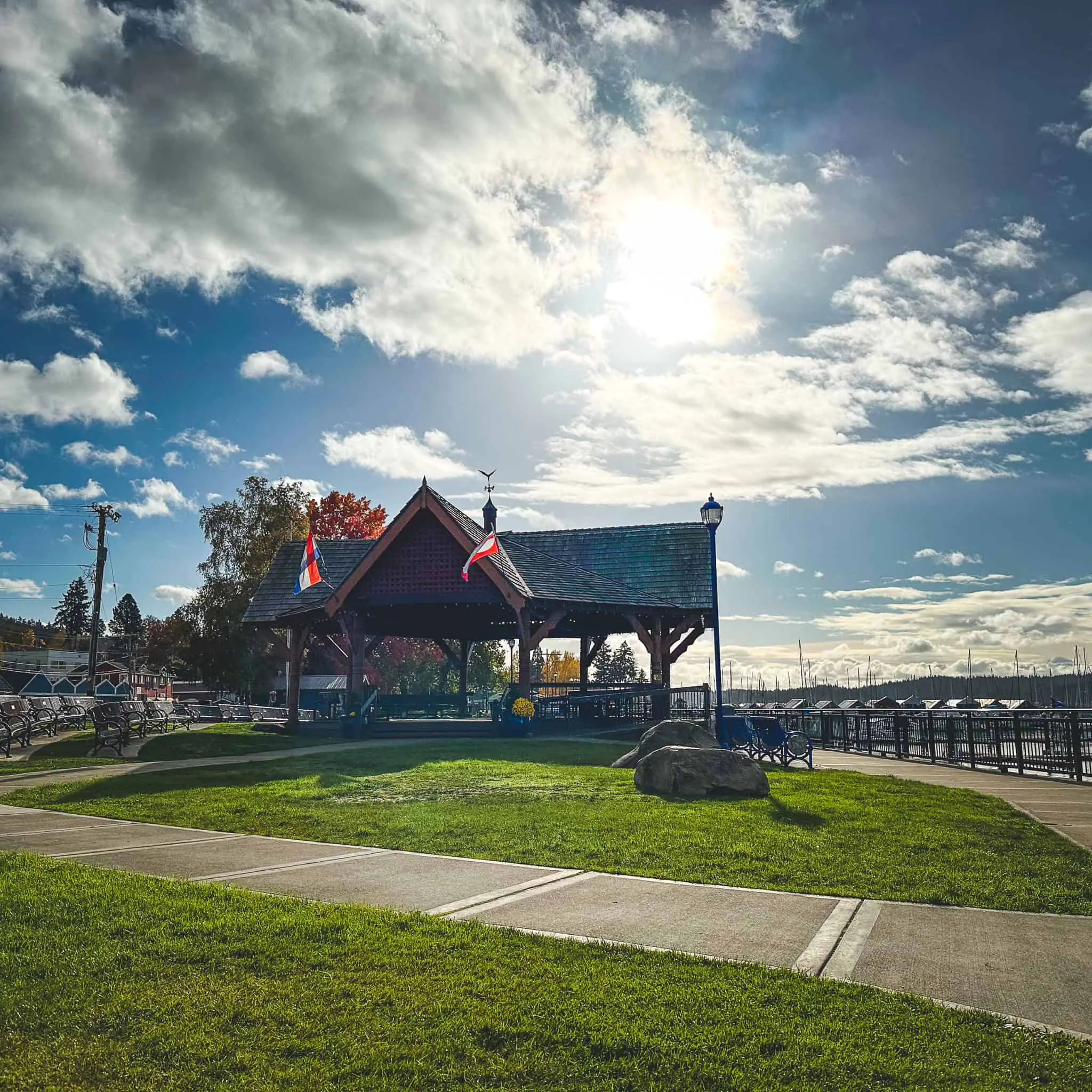 Scenic view of Poulsbo waterfront pavilion with flags and sky.