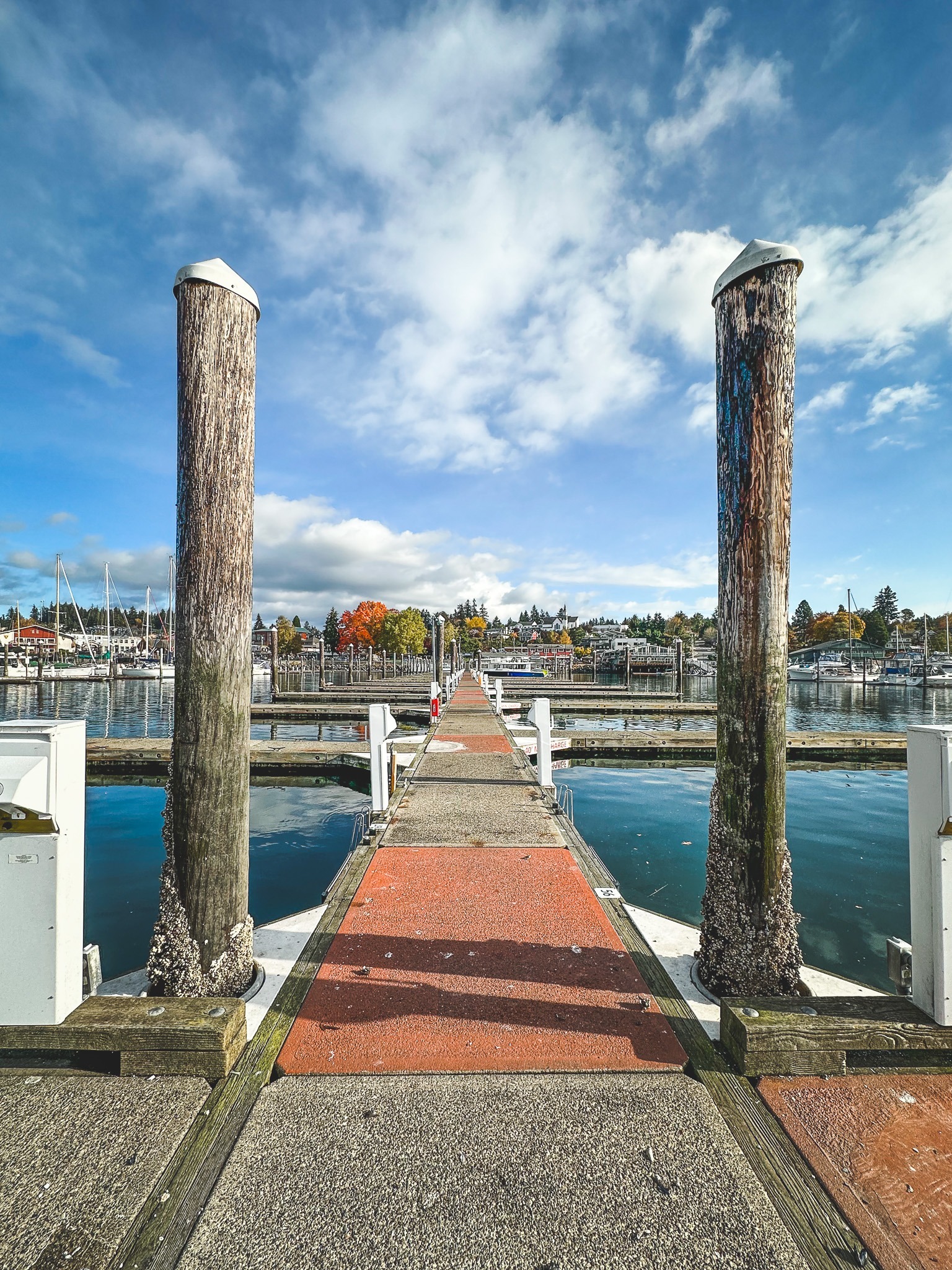 View of Poulsbo marina dock with boats and blue sky.