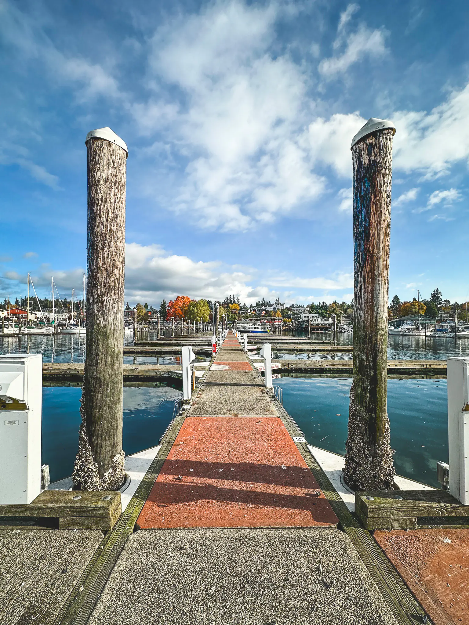 View of Poulsbo marina dock with boats and blue sky.